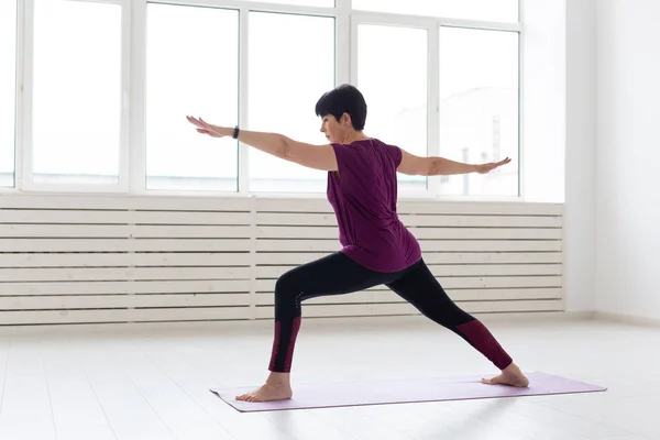 Yoga, concepto de personas - una mujer de mediana edad haciendo un yoga y tratar de hacer una asana —  Fotos de Stock
