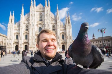 Kış seyahat, tatil ve kuşlar kavramı - yakışıklı erkek turist Milano'da ünlü Duomo Katedrali önünde selfie fotoğraf yapma komik güvercinler ile.
