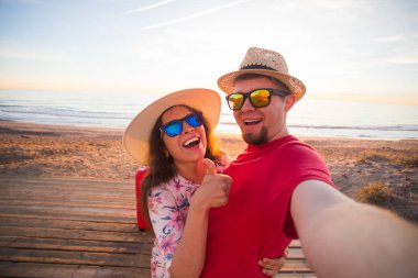 Gezi, tatil ve tatil kavramı - genç ve güzel kadın ve hasır şapkalar yakışıklı erkek arkadaşını selfie olun