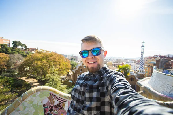 Concepto de viaje y vacaciones - Hombre feliz haciendo retrato selfie con smartphone en Park Guell, Barcelona, España . — Foto de Stock