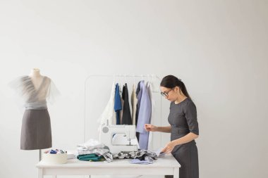 İnsanlar ve moda kavramı - genç terzi kadın dikiş makinesi giysilerini diker.