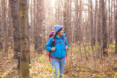 İnsanlar ve doğa kavramı - gülümseyen turist kadın portresi ormanda yürüyüş mavi ceket giymiş
