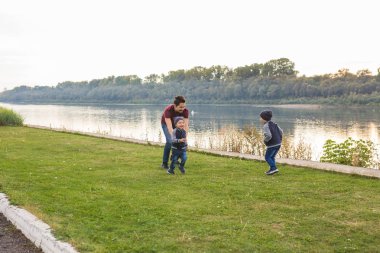 Çocukluk, aile kavramı - göl yakınındaki iki oğlu ile oynarken baba