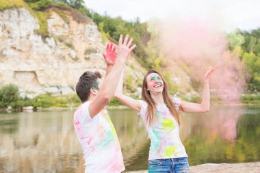 Festival holi, tatil, turizm ve doğa kavramı - çift renkli toz ile oynayan beyaz gömlek giymiş