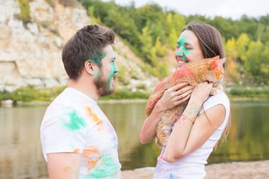 Festival holi, tatil, turizm, evde beslenen hayvan ve doğa kavramı - kadın ve erkek kedi ile portre çok renkli toz kaplı.