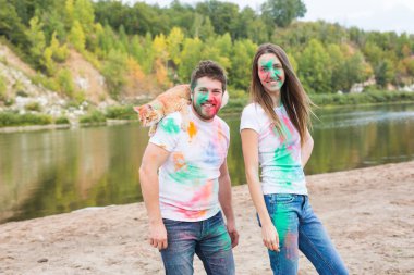 Festival holi, tatil, turizm ve doğa kavramı - çift kedi holding beyaz gömlek giymiş ve renkli tozla kaplı