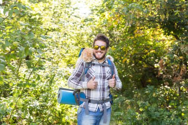 Uzun yürüyüşler, turizm ve doğa kavramı - genç seyahat etmek sırt çantası ve onun kedi ayakta orman arka plan üzerinde