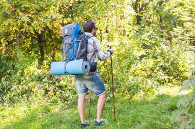 Uzun yürüyüşler, turizm ve doğa kavramı - sırt çantası konumu orman arka plan üzerinde olan genç yolcusu