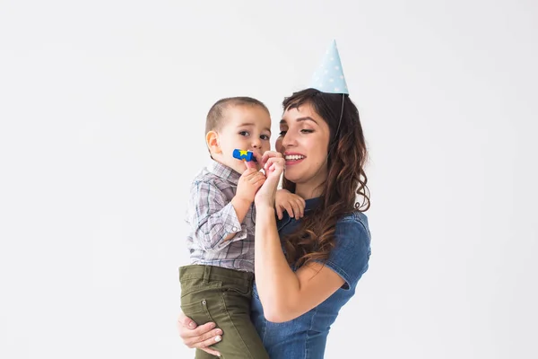 Personas, niños y concepto de vacaciones - Madre encantadora sostiene a su hijo con gorra de cumpleaños sobre fondo blanco — Foto de Stock