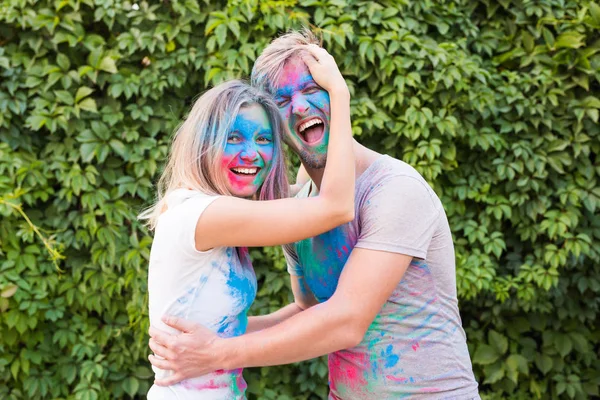 Conceito de férias, holi e pessoas - Mulher sorridente e homem posando com pó multicolorido em seus rostos — Fotografia de Stock