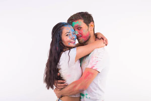 Conceito de férias, holi e pessoas - Sorrindo mulher engraçada e homem posando com pó multicolorido em seus rostos no fundo branco — Fotografia de Stock