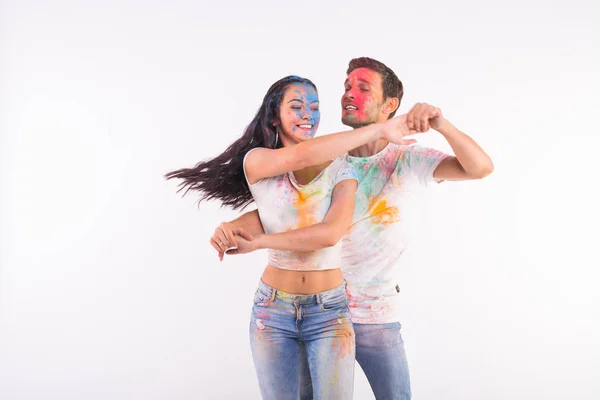 Friendship, social dance, love, festival of holi, people concept - young couple playing with colors and dancing bachata or kizomba at the festival of holi on white background — Stock Photo, Image