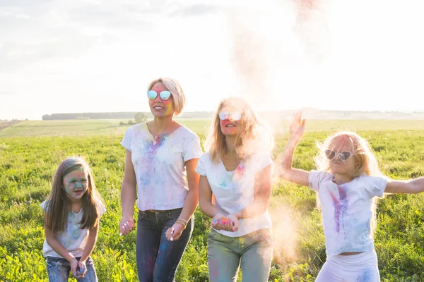 Vänskap, indiska helgdagar och människor koncept - unga kvinnor och barn som dansar på fältet sommaren på festivalen holi — Stockfoto