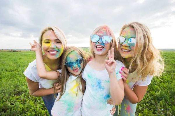 Vriendschap, feestdagen, kleur concept - portret van mooi en gelukkig vrienden bedekt met verf over de achtergrond van de natuur — Stockfoto