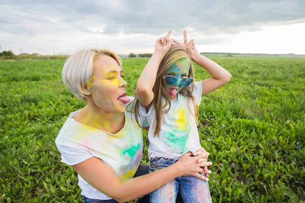 Lycka, Holi festival och helgdagar koncept - två unga kvinnor och tjej att ha kul på holi festival — Stockfoto