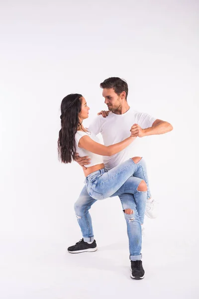 Pareja joven bailando baile social latino bachata, merengue, salsa. Dos poses de elegancia sobre fondo blanco — Foto de Stock