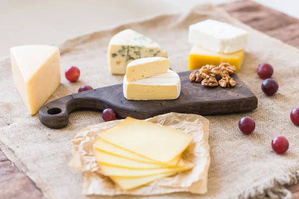 Fresh products. Cheese, brie, Camembert, grapes and nuts on rustic table.