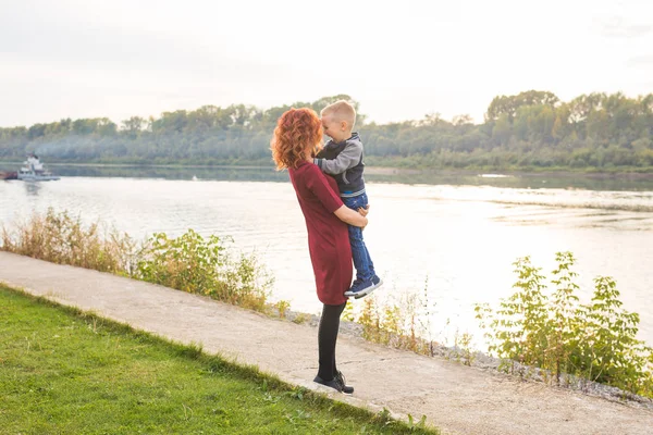 Mutterschafts- und Kinderkonzept - junge Mutter mit Sohn im Arm in der Nähe des Flusses — Stockfoto