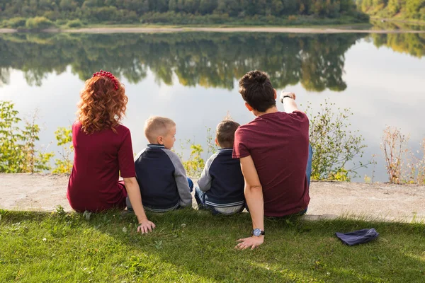 Childhood and nature concept - Family with little sons sitting on the green grass — Stock Photo, Image