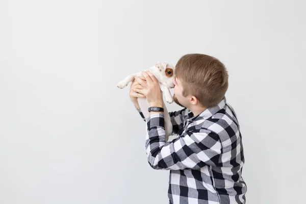 Lidé, domácí zvířata a zvířata koncept - mladý muž líbání jack russell teriér štěně na bílém pozadí s kopií prostor — Stock fotografie