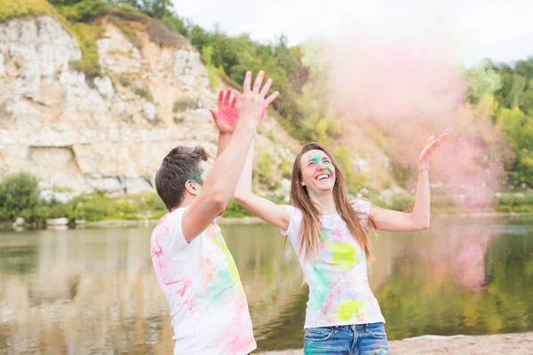 Festival holi, vacaciones, turismo y concepto de la naturaleza - Pareja vestida con camisas blancas jugando con polvo de colores —  Fotos de Stock