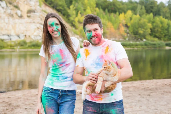Festival holi, Tourismus und Naturkonzept - Portrait von Frau und Mann mit Katze bedeckt mehrfarbigem Staub — Stockfoto