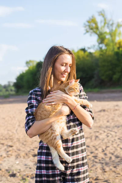 People, summer tourism and nature concept - young woman with cat on the beach — Stock Photo, Image