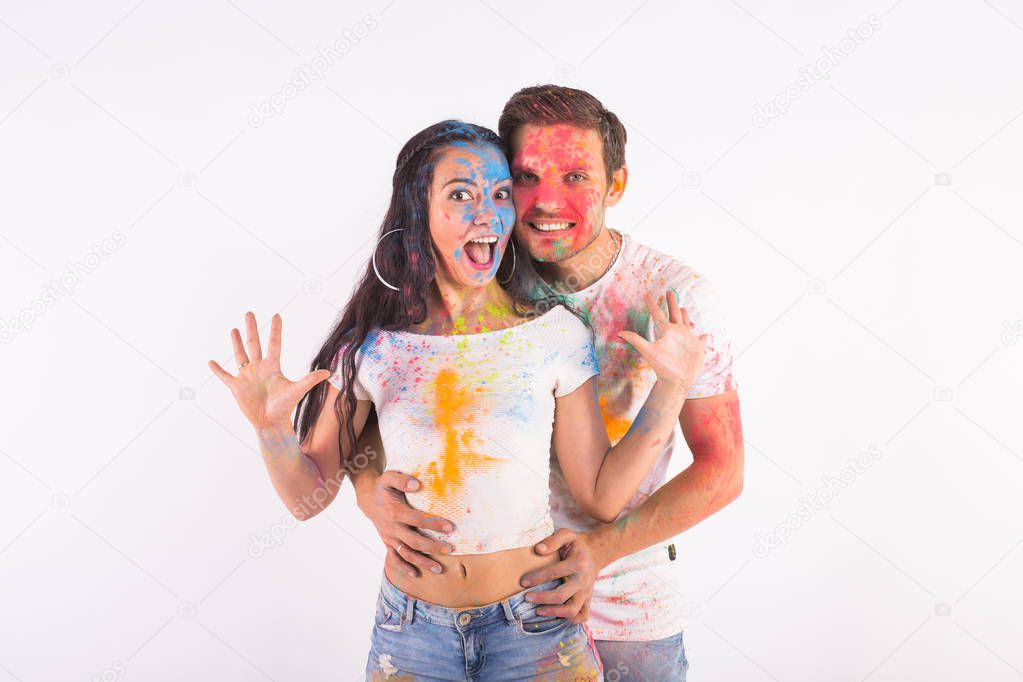 Festival of holi, friendship - young people playing with colors at the festival of holi on white background