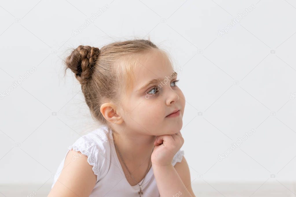 Children and kids concept - Portrait of beautiful little child girl holding her chin on hand and looking up