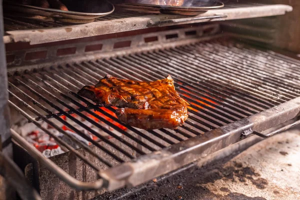 Food, craft and delicious concept - cooking steak on a grill — Stock Photo, Image