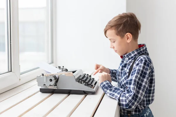 Día Mundial del concepto de escritor - Niño con una vieja máquina de escribir sobre el fondo de la ventana —  Fotos de Stock