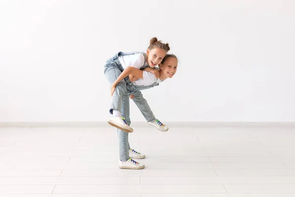 Concept de famille et d'amour - heureuse fille jumelle donnant tour de tirelire à sa sœur riante — Photo