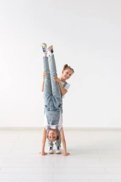 Personas, niños y concepto acrobático - hermanas gemelas haciendo ejercicios sobre fondo blanco — Foto de Stock