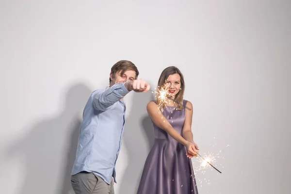 Festa, evento e conceito de férias - homem e mulher brincando com faíscas sobre fundo cinza — Fotografia de Stock