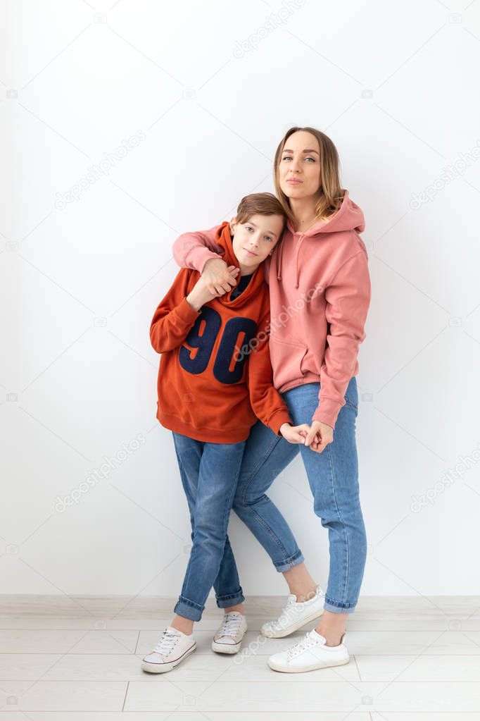 Mothers day, children and family concept - teen boy hugging his mom on white background