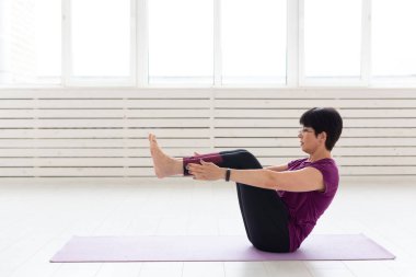 Yoga, meditasyon, insanlar kavramı - orta yaşlı bir kadın spor salonunda bir yoga yaparken
