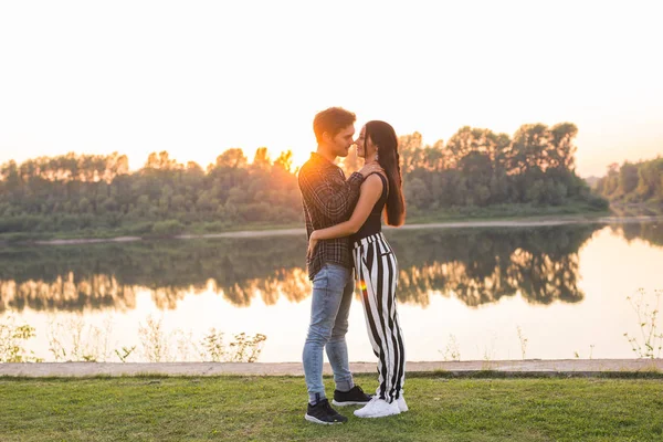 Ρομαντική και άνθρωποι έννοια - νεαρό ζευγάρι αγκάλιασμα μαζί κοντά στο ποτάμι ή λίμνη και απολαμβάνοντας την θερινή ώρα — Φωτογραφία Αρχείου