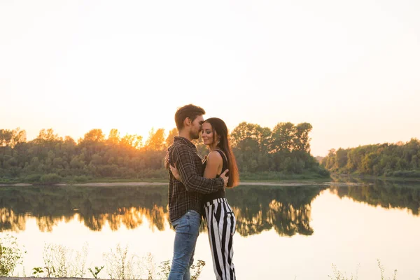 Concetto romantico e popolare - giovane coppia che si abbraccia insieme vicino al fiume o al lago e si gode l'ora legale — Foto Stock