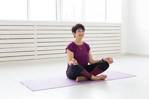 Yoga, harmony, people concept - Middle aged woman sitting in lotus position
