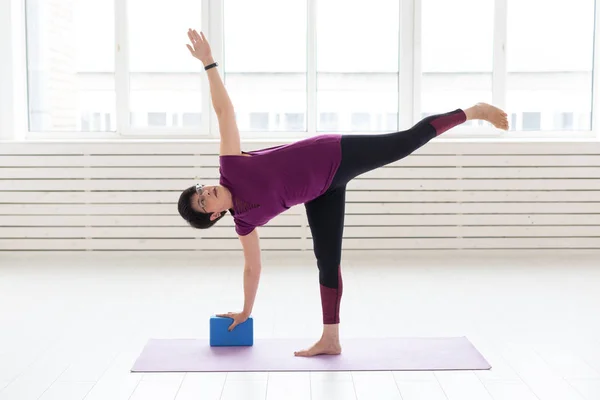 Personas, yoga, deporte y concepto de salud - Mujer de mediana edad practicando yoga, utilizando cubo de estiramiento —  Fotos de Stock