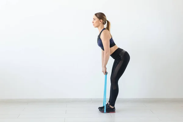 Concepto de personas, deporte y fitness: entrenamiento de mujeres jóvenes con banda de entrenamiento en el gimnasio — Foto de Stock