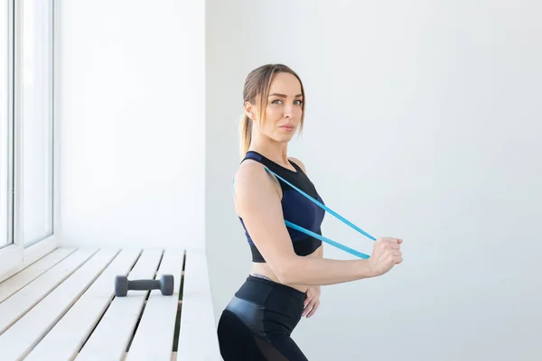 Concepto de personas, deporte y fitness: entrenamiento de mujeres jóvenes con banda de entrenamiento en el gimnasio — Foto de Stock