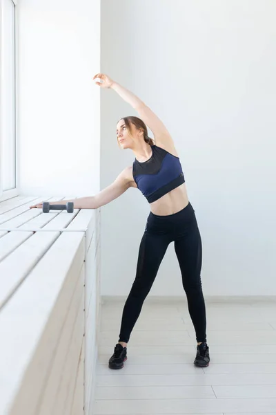 Gente, deporte y fitness concepto - mujer joven haciendo ejercicios que se extienden cerca de la ventana — Foto de Stock