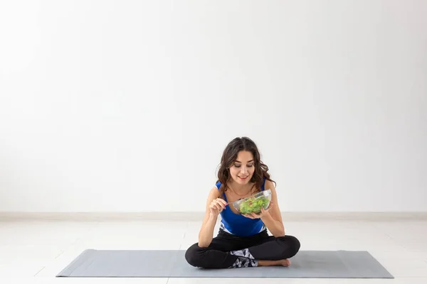 Estilo de vida saludable, personas y concepto deportivo - Mujer de yoga con un tazón de ensalada de verduras — Foto de Stock