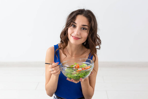 Food, healthy lifestyle, people concept - Young woman eating salad and smiling