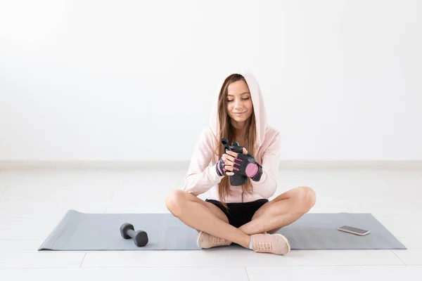 Estilo de vida saludable, personas y concepto deportivo - Mujer sentada en una esterilla de yoga y bebiendo agua después de un duro entrenamiento —  Fotos de Stock