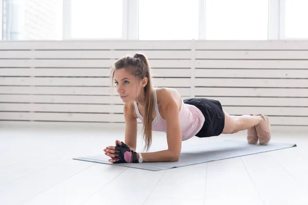 Concepto de deporte, yoga y personas: una mujer joven está haciendo una tabla, tomando un equilibrio —  Fotos de Stock