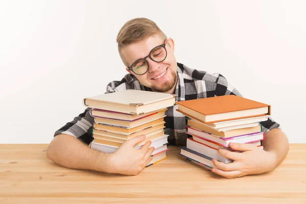 Concepto de personas, conocimiento y educación - hombre sonriente sentado en la mesa de madera con libros — Foto de Stock