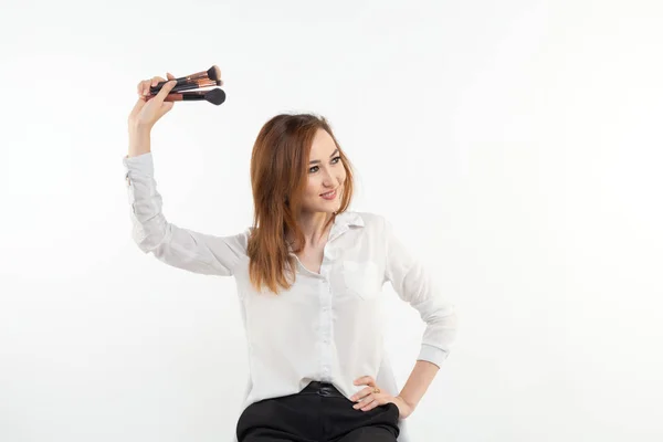 Make-up artiest, schoonheid en mensen concept - mooie Koreaanse jonge vrouw die make-up borstels op witte achtergrond — Stockfoto