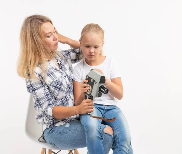 Foto, fotógrafo y concepto de cámara retro - mujer joven y su hija adolescente usando cámara vintage sobre fondo blanco —  Fotos de Stock